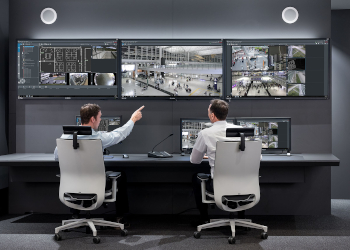 control room; operator; monitors; monitor wall; bosch vido management system; user interface; two persons; men, pointing to monitor; security room; security control room